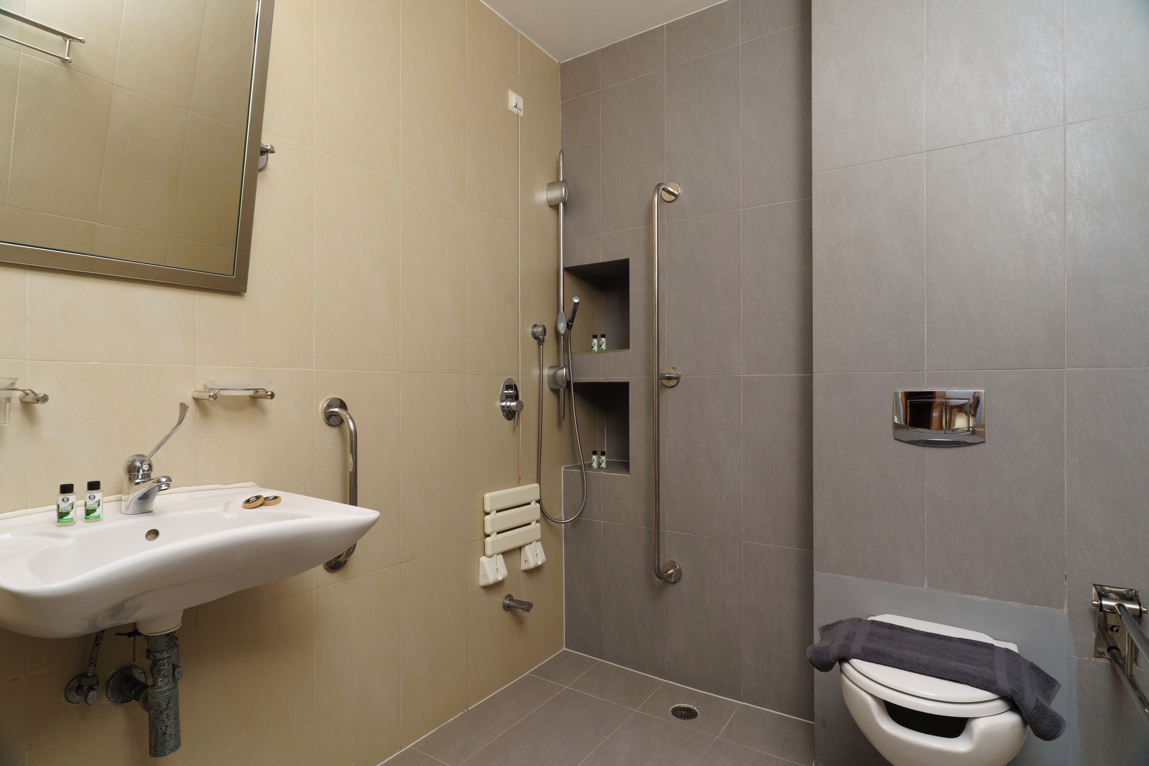 Un baño moderno con lavabo, espejo, ducha e inodoro.
