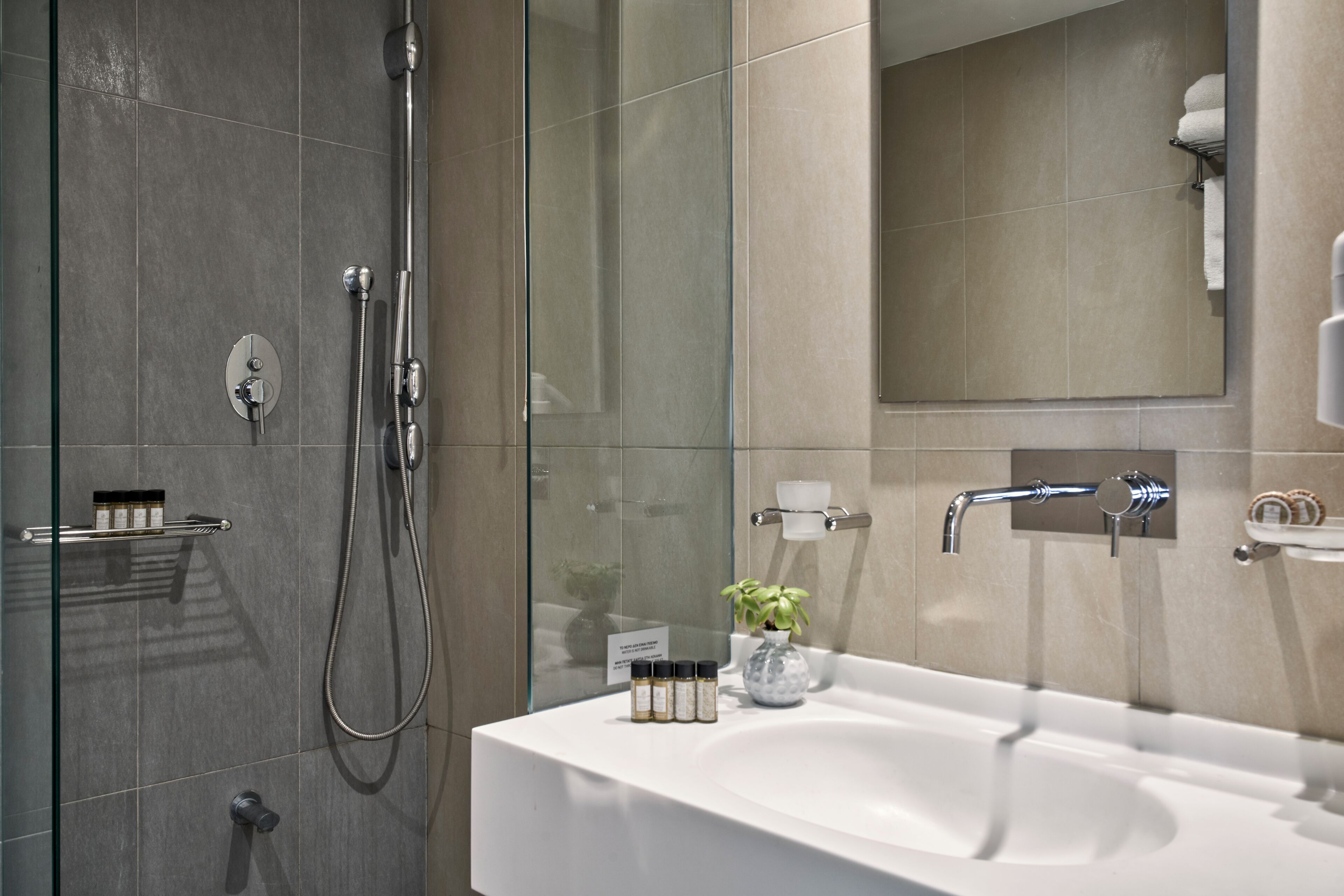 Une salle de bain moderne avec une douche à parois de verre, un lavabo blanc et un miroir au-dessus.