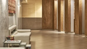 A modern hotel lobby with a reception desk, seating area, and wooden paneling. - Oxygen Favie by GHH (Tinos)