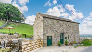 A stone building with a green door, a wooden gate, and potted plants. - Pogles Wood Cottage (Skipton)