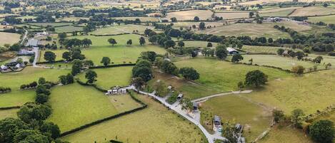 An aerial view of a rural landscape with fields, scattered houses, and a winding road.