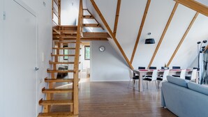 Un loft espacioso con una escalera de madera, un comedor y una sala de estar con sofá.
