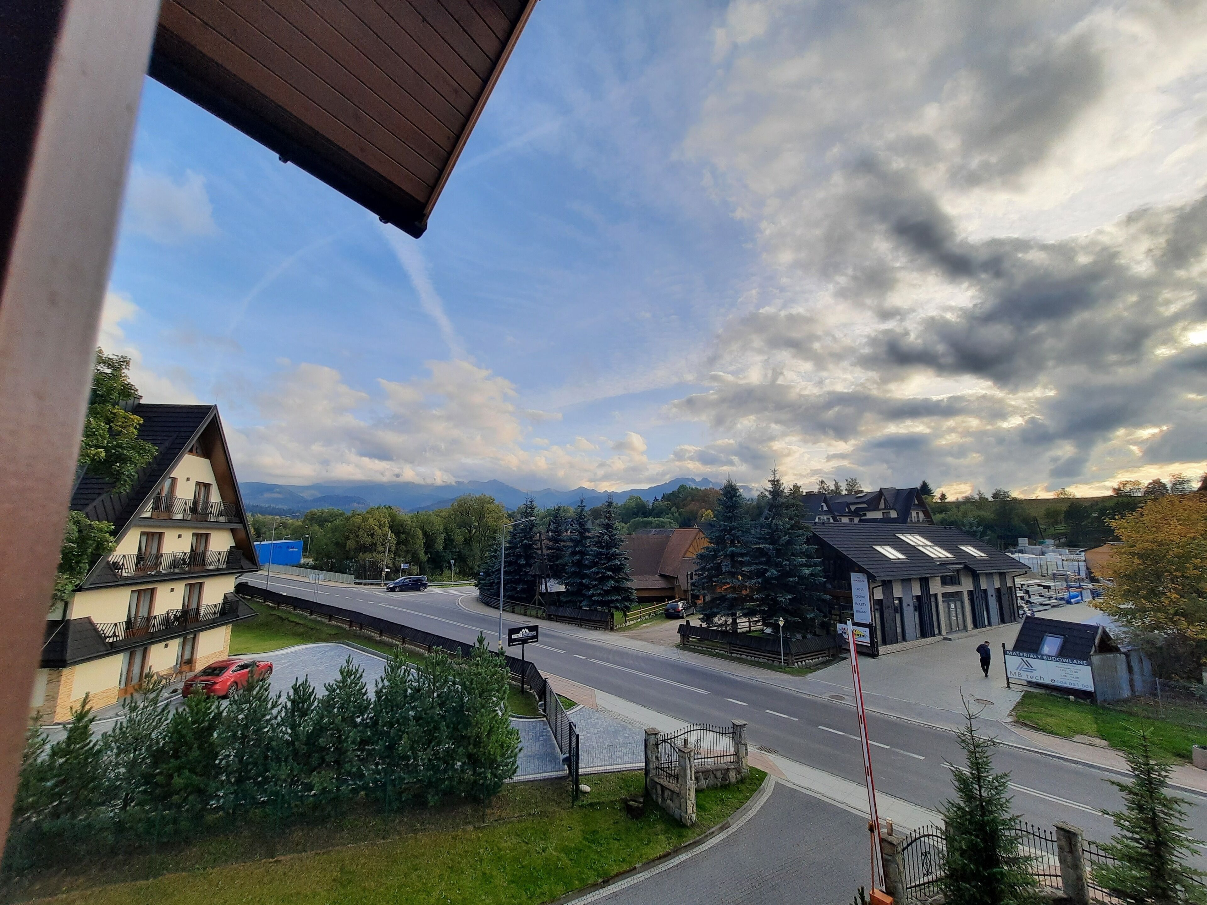 Un quartier résidentiel avec des maisons, une route et une chaîne de montagnes en arrière-plan.