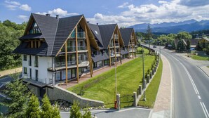 Una hilera de casas modernas, de varios pisos, con amplias ventanas y balcones, frente a un paisaje de montañas y cielo despejado.
