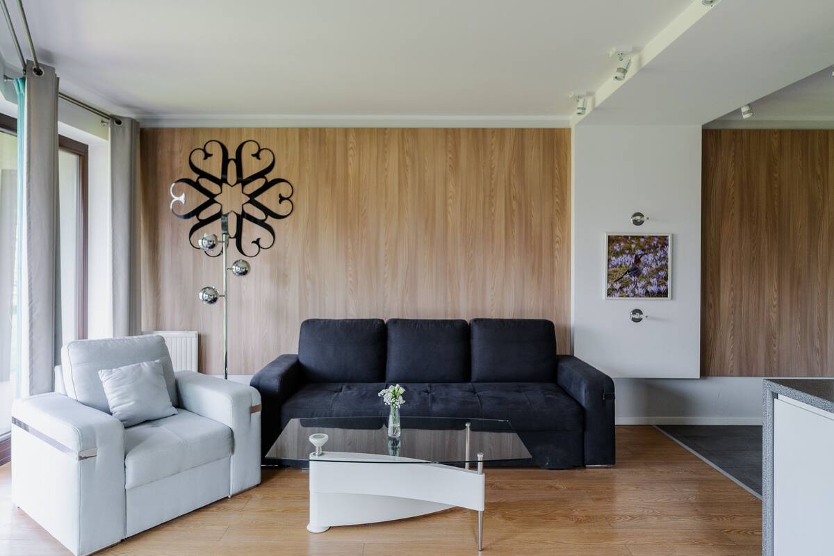 Una sala de estar moderna con un sillón gris claro, un sofá negro y una mesa de centro de cristal.