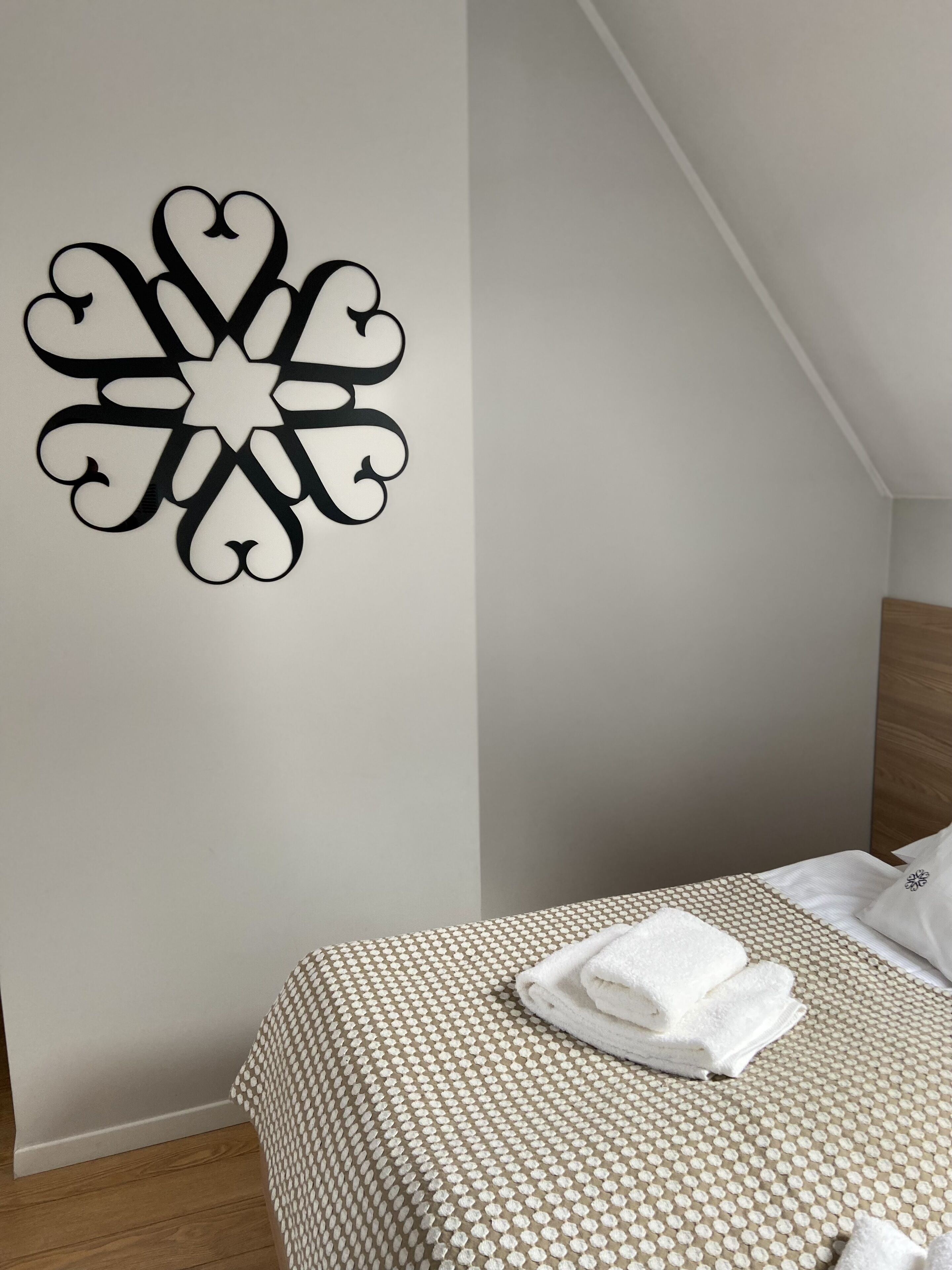 A neatly made bed with a patterned bedspread and a decorative wall piece.