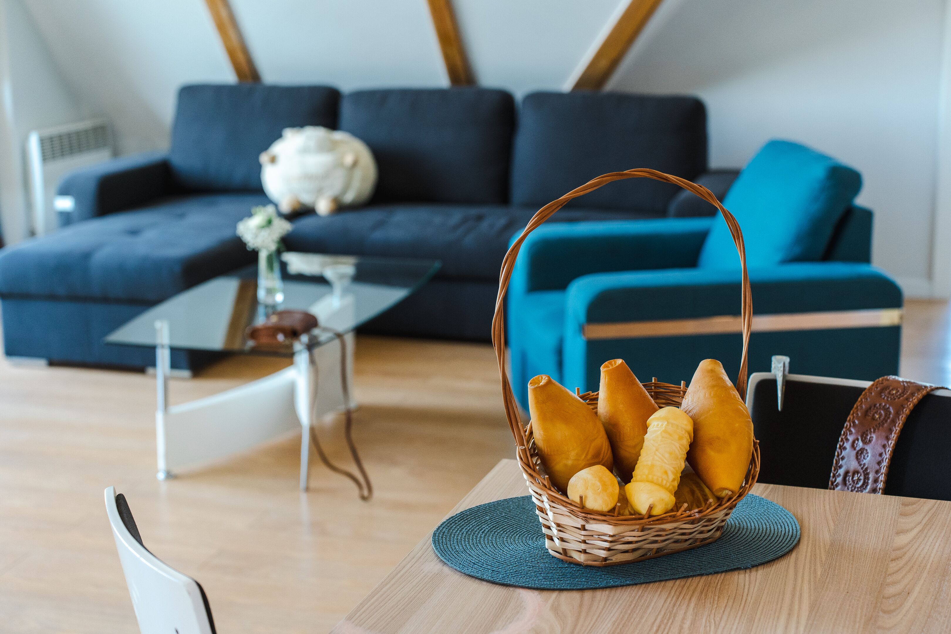 Un salón con un sofá azul oscuro, una mesa de centro y una cesta de mimbre con pan sobre una mesa de madera.