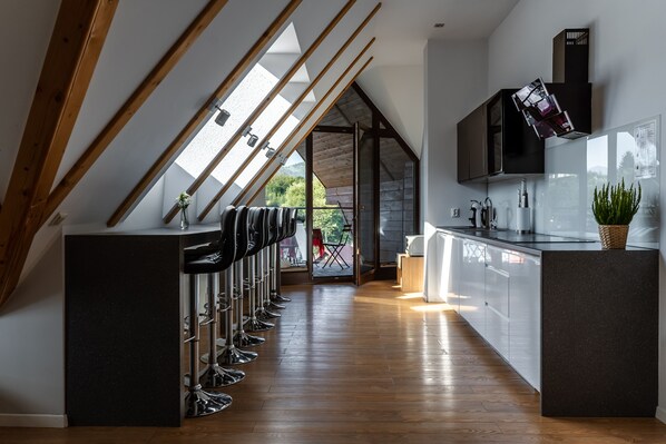 A modern kitchen with a central island, bar stools, and a view to an outdoor patio.