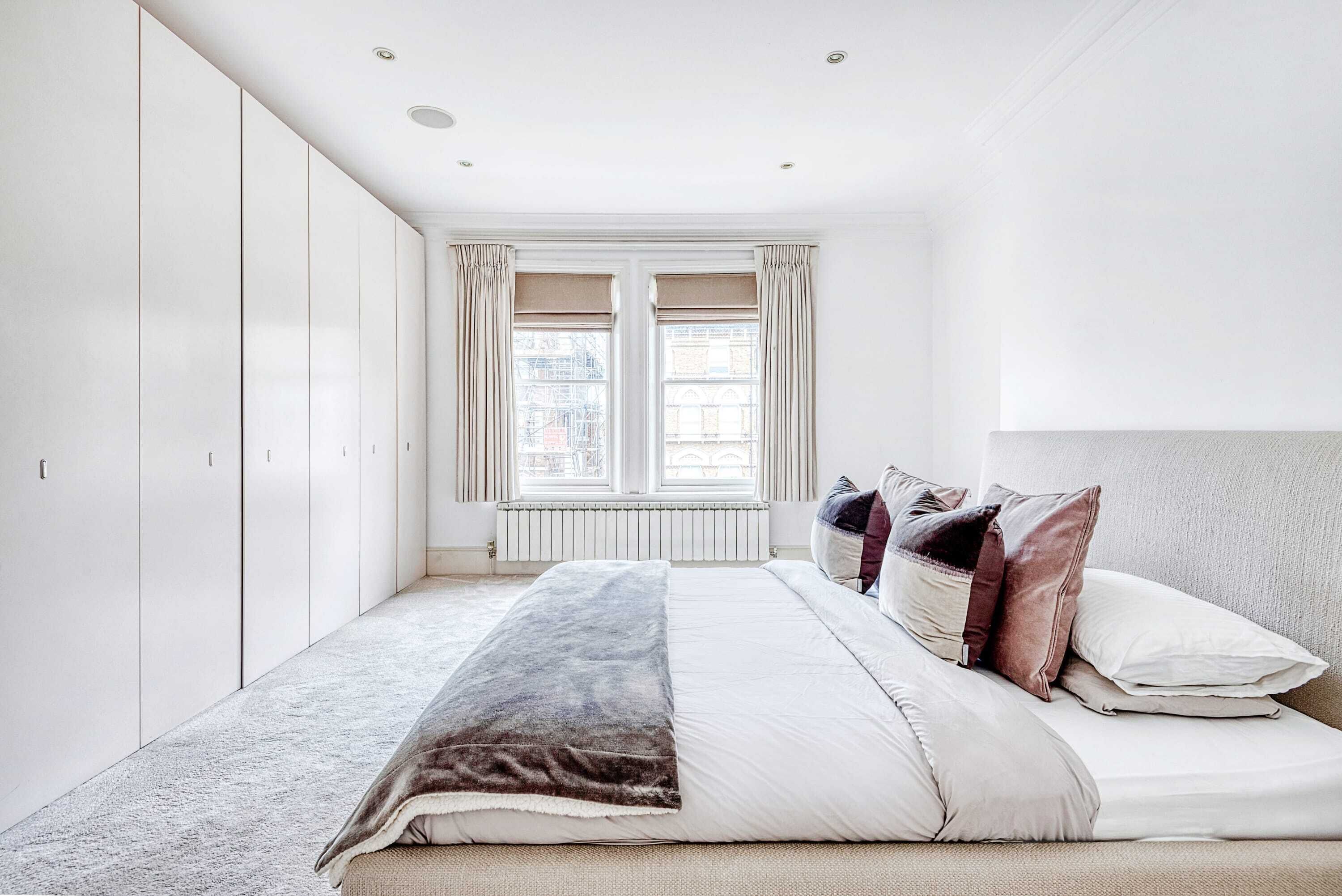 Ein Schlafzimmer mit einem Bett, einem Heizkörper und einem Fenster mit Vorhängen.