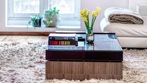 A living room with a coffee table holding books and a vase with flowers.