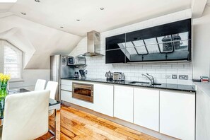 A modern kitchen with white cabinets, a black countertop, and a large window.