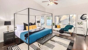 A modern bedroom with a four-poster bed, a ceiling fan, and a view of the outdoors. - Four BR Modern Tempe Oasis|Heated Pool + Game Room (Tempe)