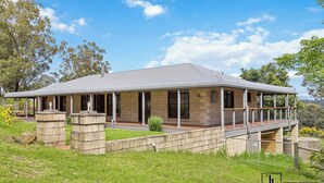 A two-story house with a covered porch, stone pillars, and a stone retaining wall. - Minutes to Malua Bay Beach | Sunset Vista Retreat (Malua Bay)