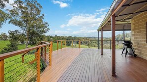 A wooden deck with a metal railing overlooking a grassy landscape. - Minutes to Malua Bay Beach | Sunset Vista Retreat (Malua Bay)