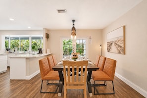 A modern dining area with a central island, wooden chairs, and a chandelier.