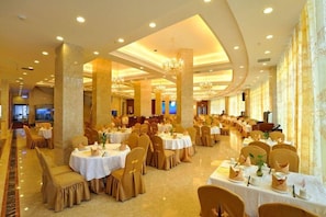 A banquet hall with multiple round tables, chairs, and chandeliers. - Golden Diamond Hotel (Zhaoqing)