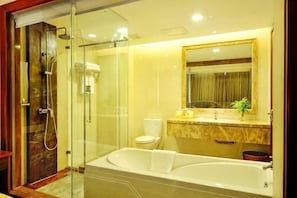 A modern bathroom with a glass-enclosed shower, a large bathtub, and a marble vanity.