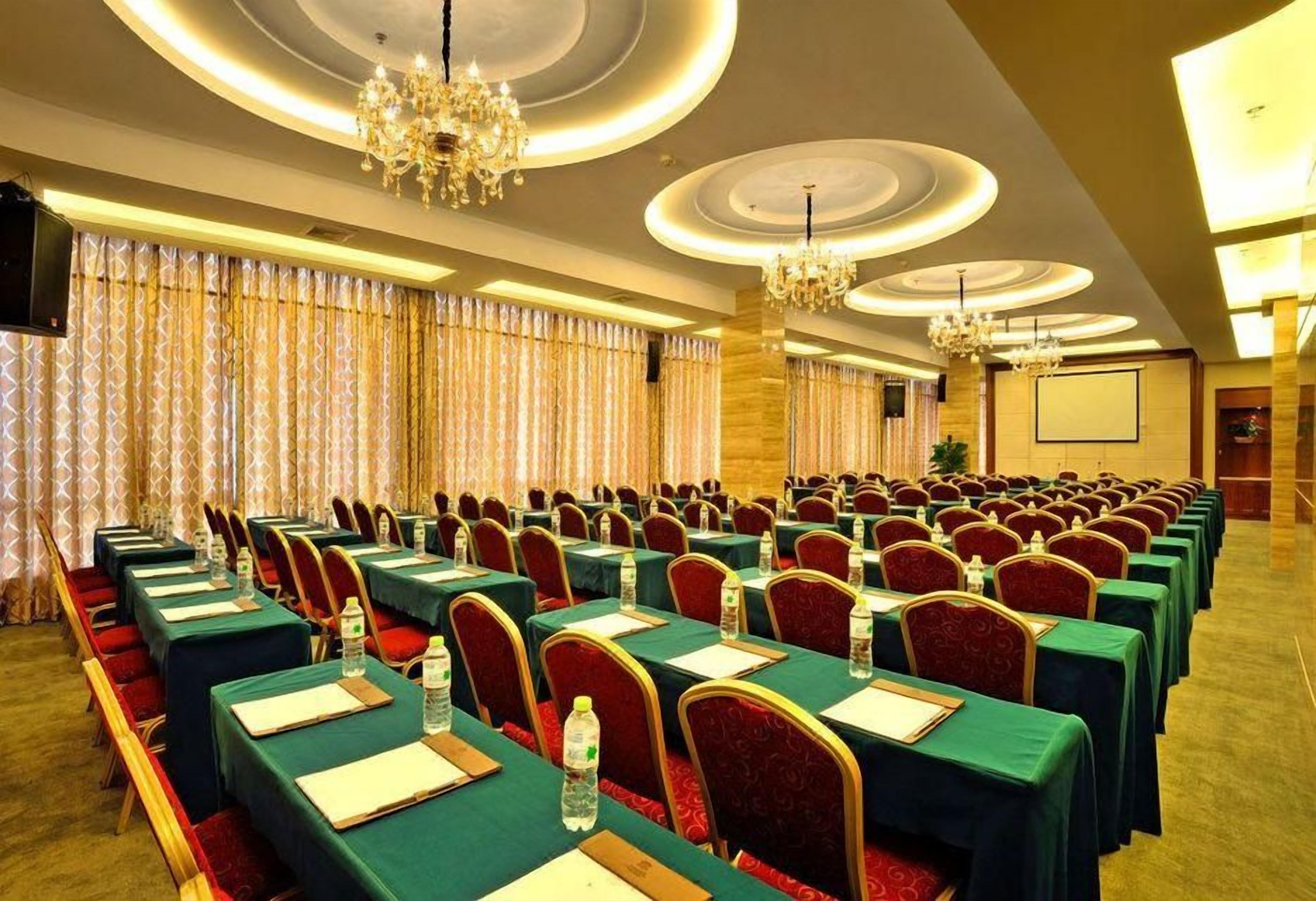 A conference room with rows of tables, chairs, and a chandelier.