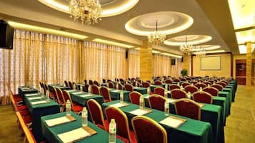 A conference room with rows of tables, chairs, and a chandelier.