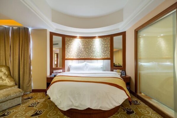 A hotel room with a large bed, a sitting area with a chair, a nightstand, and a large window. - Golden Diamond Hotel (Zhaoqing)