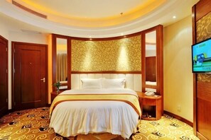 Une chambre d’hôtel avec un grand lit, une télévision, une tête de lit en bois et une moquette à motifs.