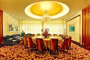 Un comedor con una mesa redonda, sillas, una araña y una alfombra estampada.