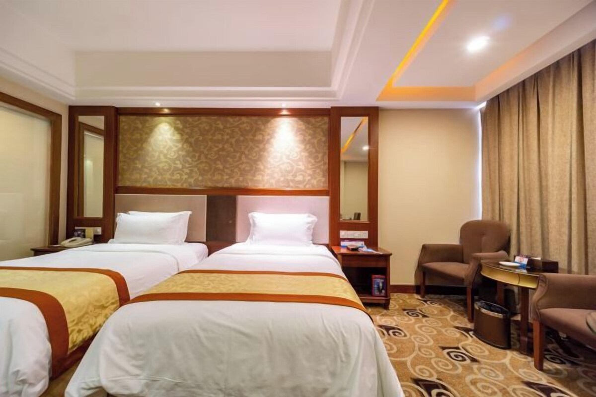 A hotel room with two beds, a desk, a chair, and a large mirror.