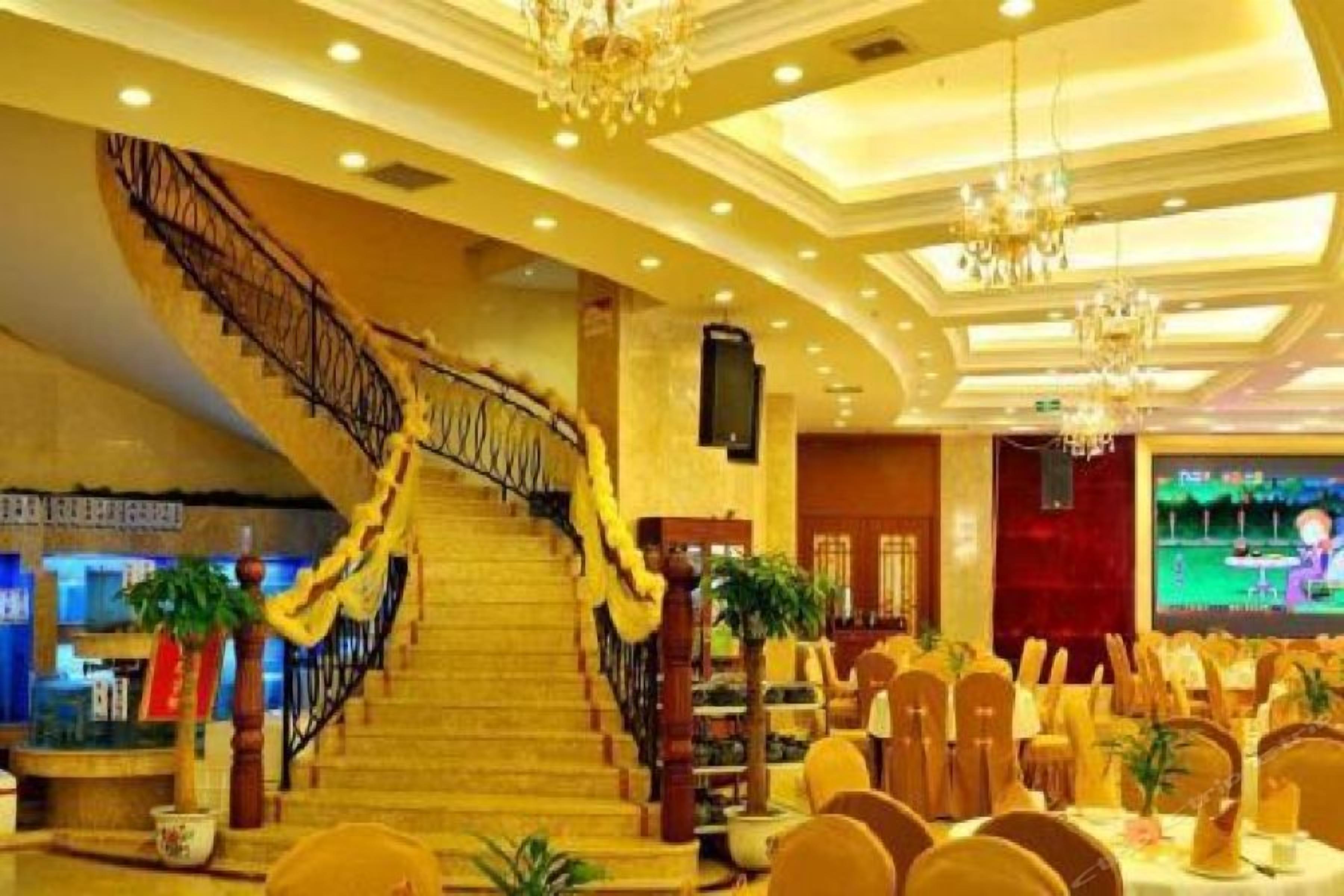 A hotel lobby with a grand staircase, chandeliers, and a conference room setup.