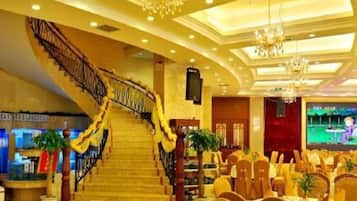 A hotel lobby with a grand staircase, chandeliers, and a conference room setup.
