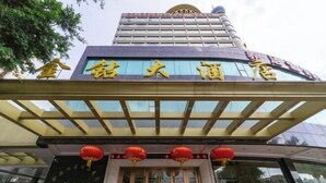 Entrada de un hotel con un cartel grande en caracteres chinos, fachada de vidrio y faroles rojos sobre la puerta.
