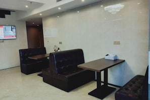 Un moderno hall de hotel con asientos de cuero, un mostrador de recepción y un televisor de pantalla plana.