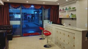 A hotel lobby with a reception desk, red bar stools, a chandelier, and a view of the street outside. - Guang'an Yandu Hotel (Guang'an)
