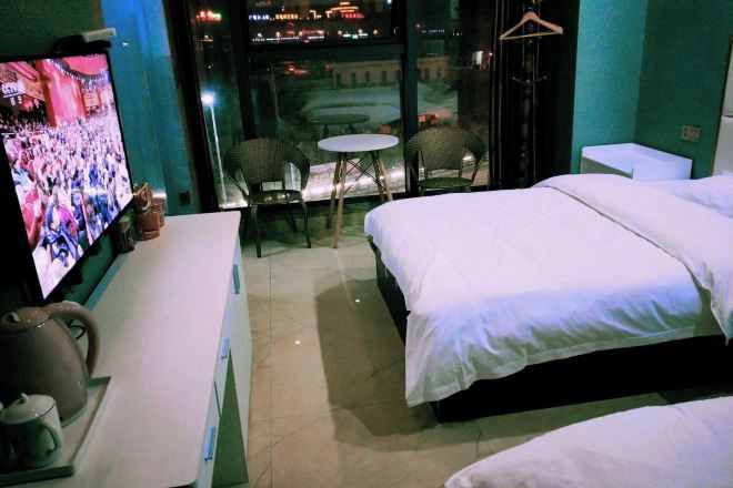 Una habitación de hotel con una cama, un televisor, una mesita y sillas.