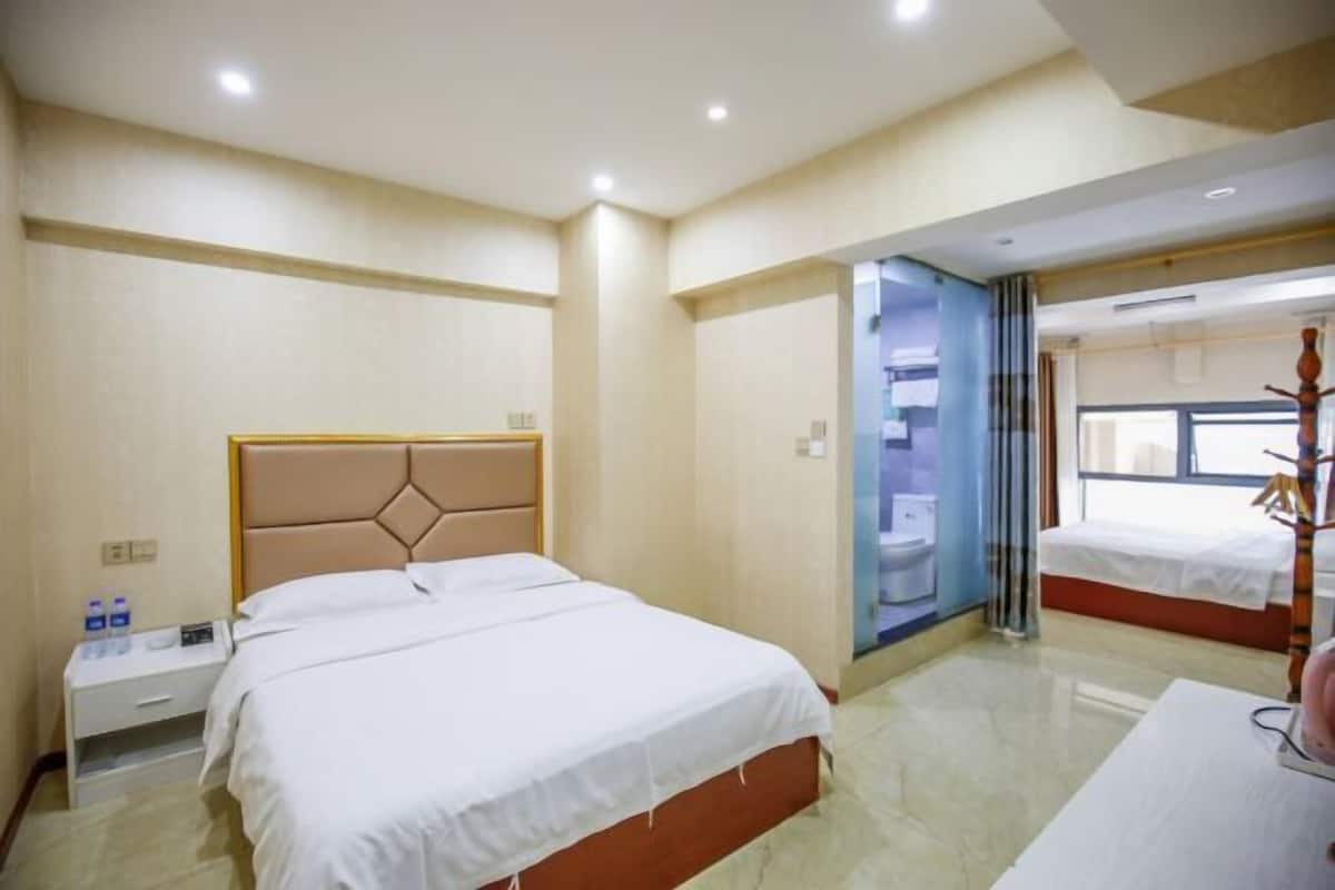 Habitación de hotel con una cama grande, una mesita de noche con lámpara y una ventana con cortinas.