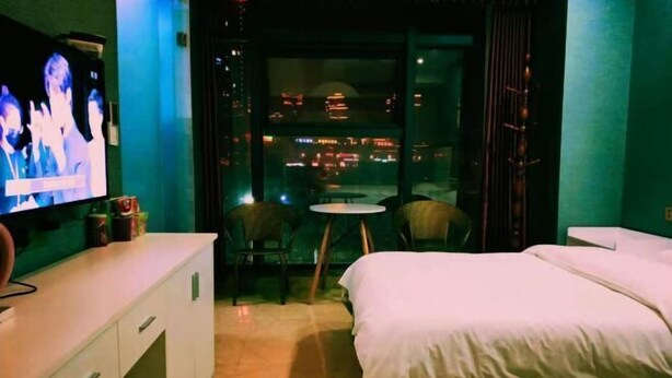 A hotel room with a bed, a TV, a small table, and a chair. - Guang'an Yandu Hotel (Guang'an)