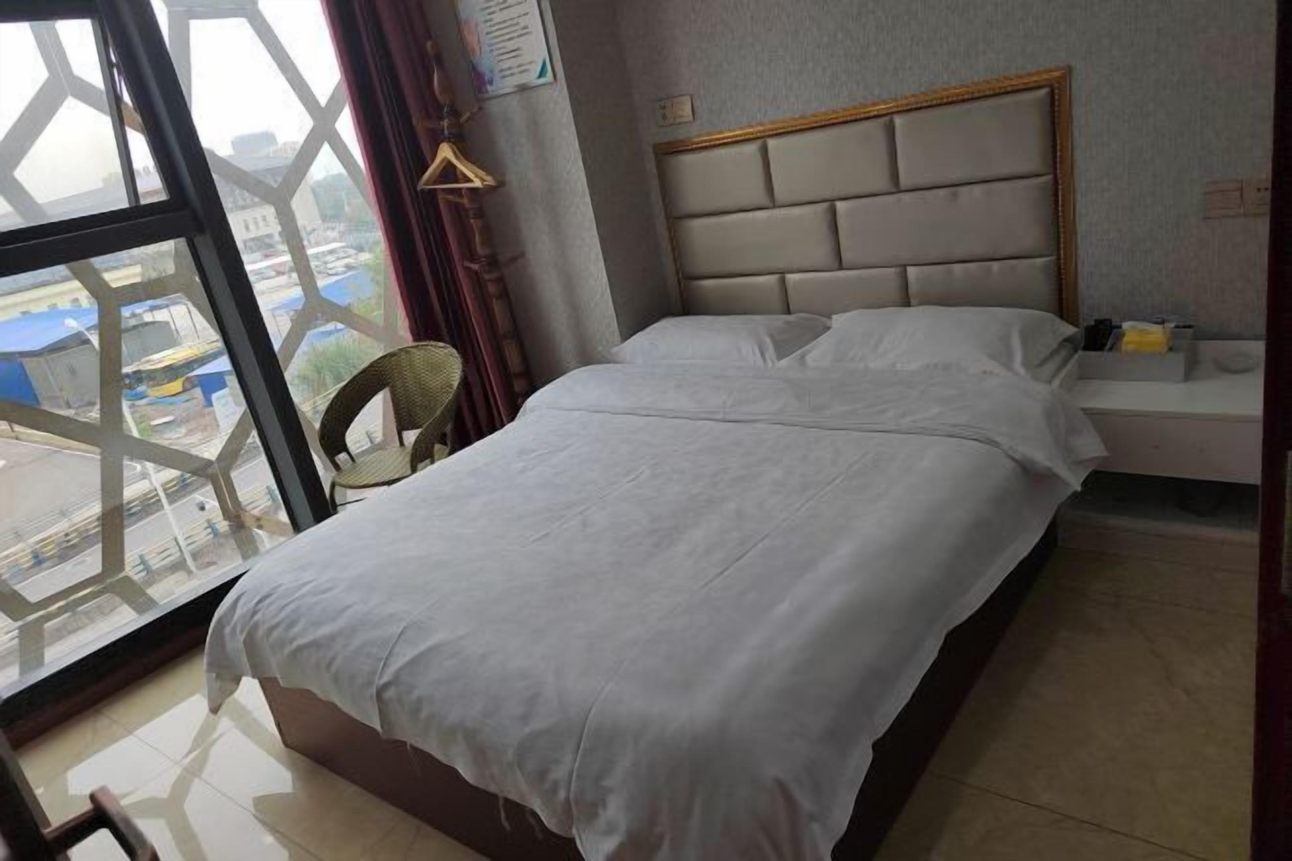 Habitació d'hotel amb un llit, una taula petita, una cadira i una finestra amb vista a l'exterior.