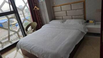 Habitació d'hotel amb un llit, una taula petita, una cadira i una finestra amb vista a l'exterior.