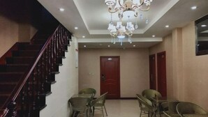 A hotel lobby with a staircase, a chandelier, and a dining area with wicker chairs. - Guang'an Yandu Hotel (Guang'an)