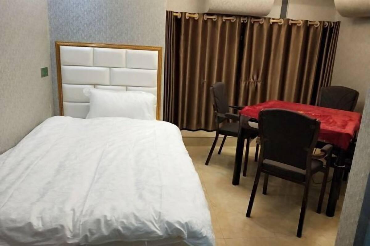 Una habitación de hotel con cama, una mesa de comedor con sillas y una cortina.