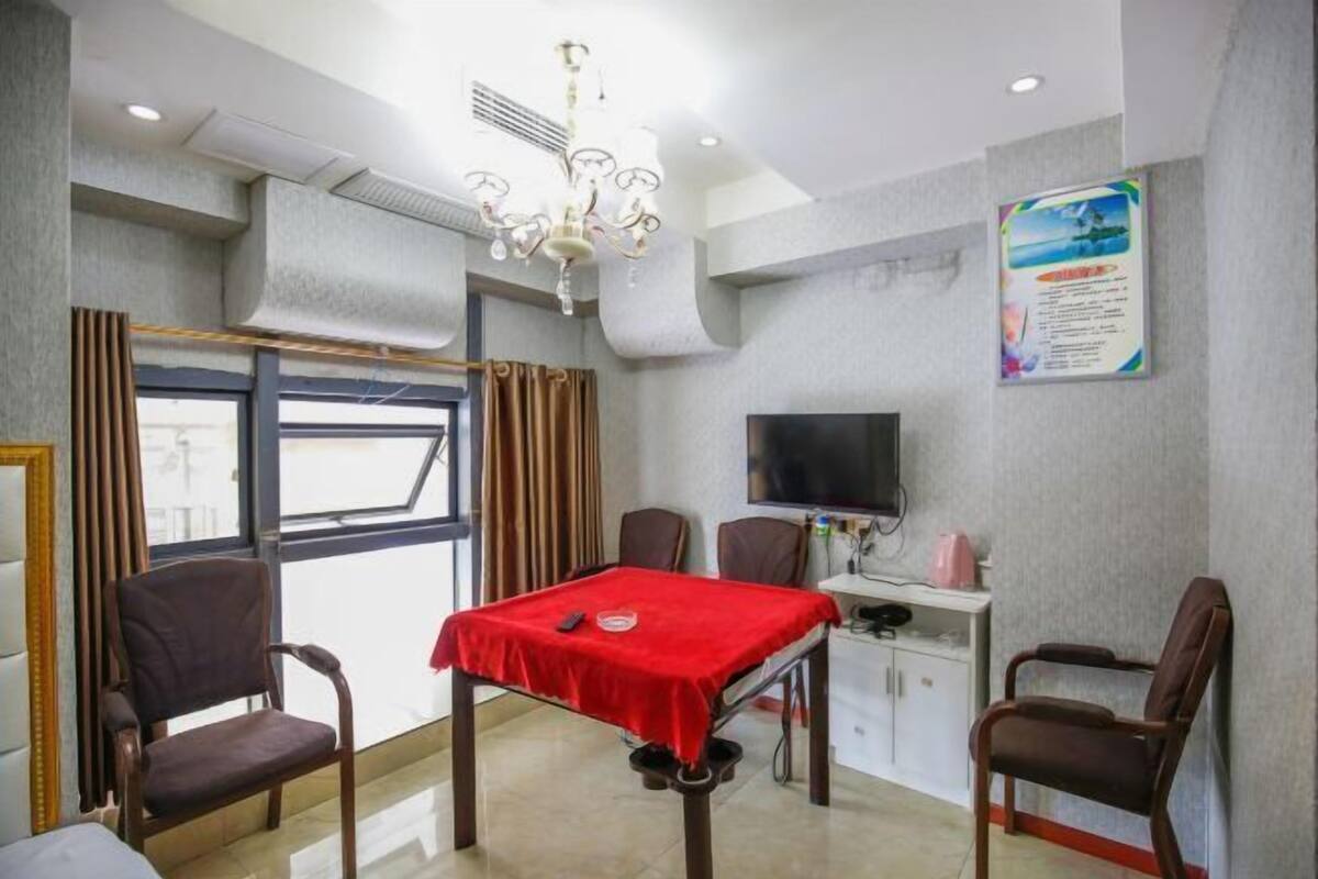 Habitación de hotel con una mesa de comedor, cuatro sillas, un televisor y una ventana con cortinas.