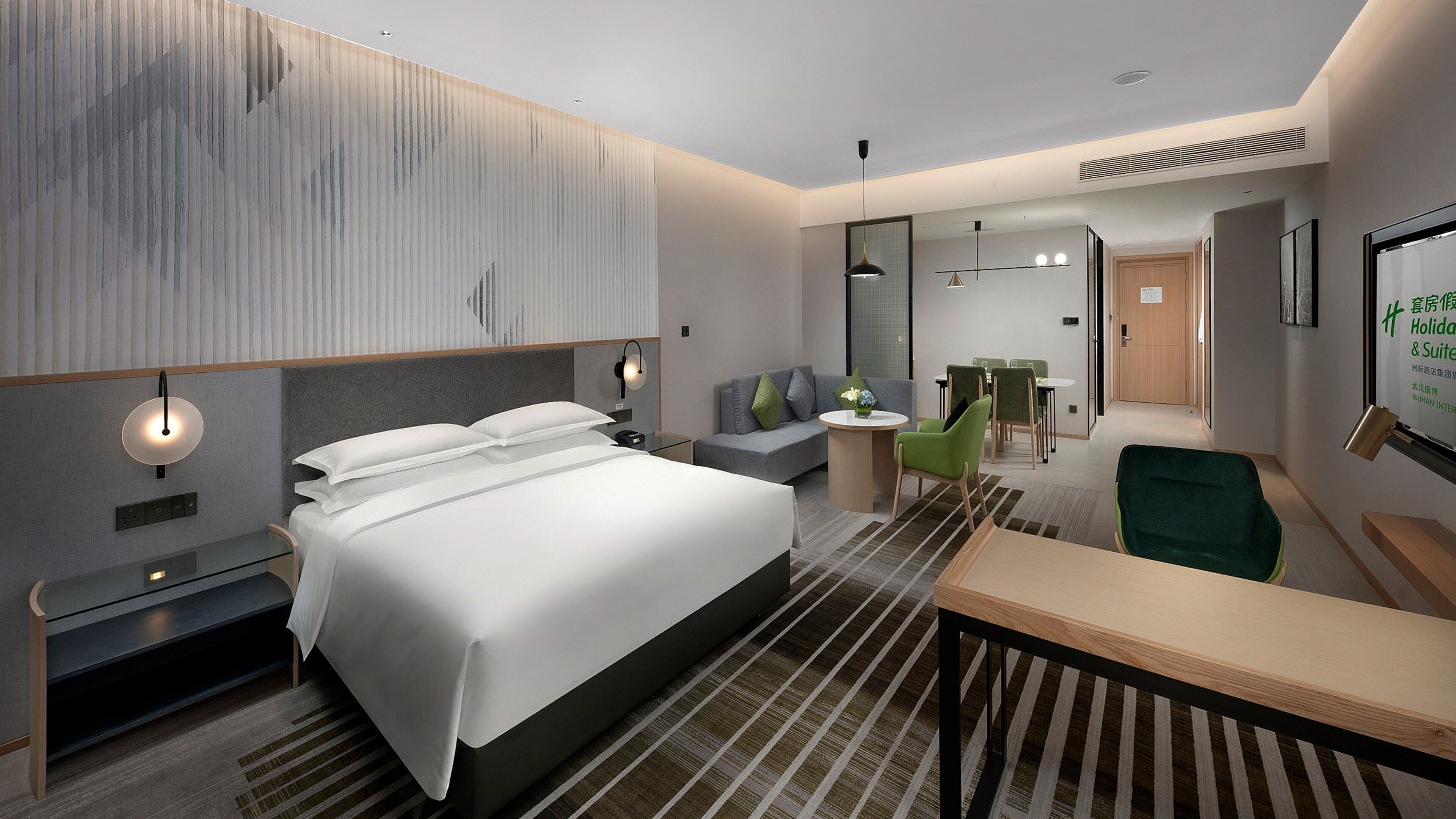 Moderni hotellihuone, jossa on suuri sänky, työpöytä, sohva ja ruokailutila.