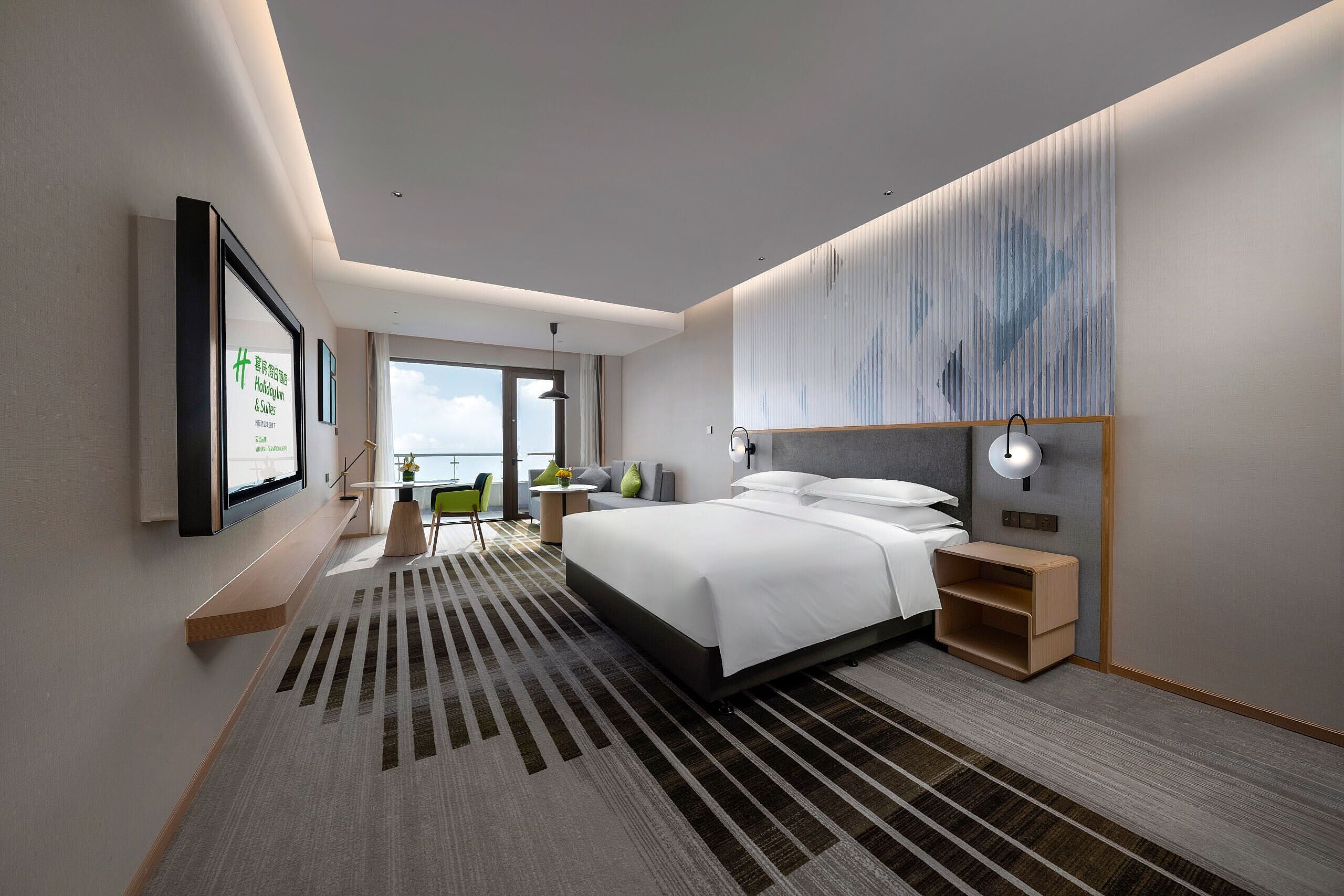 A modern hotel room with a large bed, a desk, and a view of the sky.