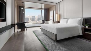 Een moderne hotelkamer met een groot bed, een bureau, een stoel en uitzicht op de stad.