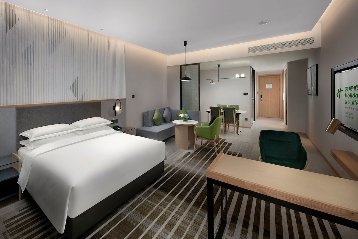Una habitación de hotel moderna con una cama grande, un escritorio, un sofá y un área de comedor con sillas.