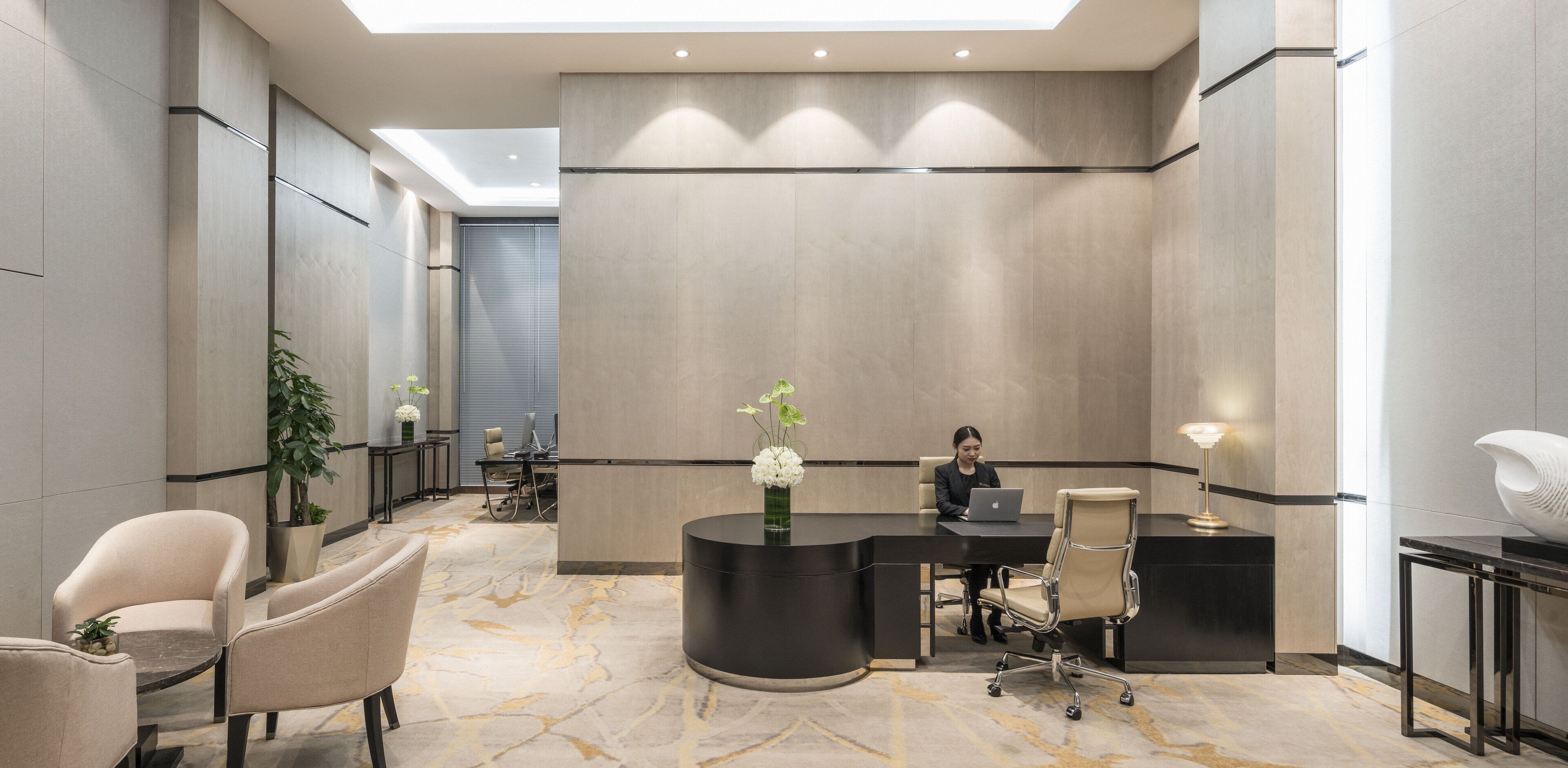 A modern hotel lobby with a reception desk, seating area, and a large window.