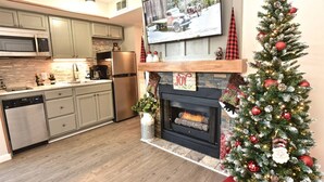 Una cocina moderna con gabinetes grises, electrodomésticos de acero inoxidable y una chimenea decorada con un árbol de Navidad.