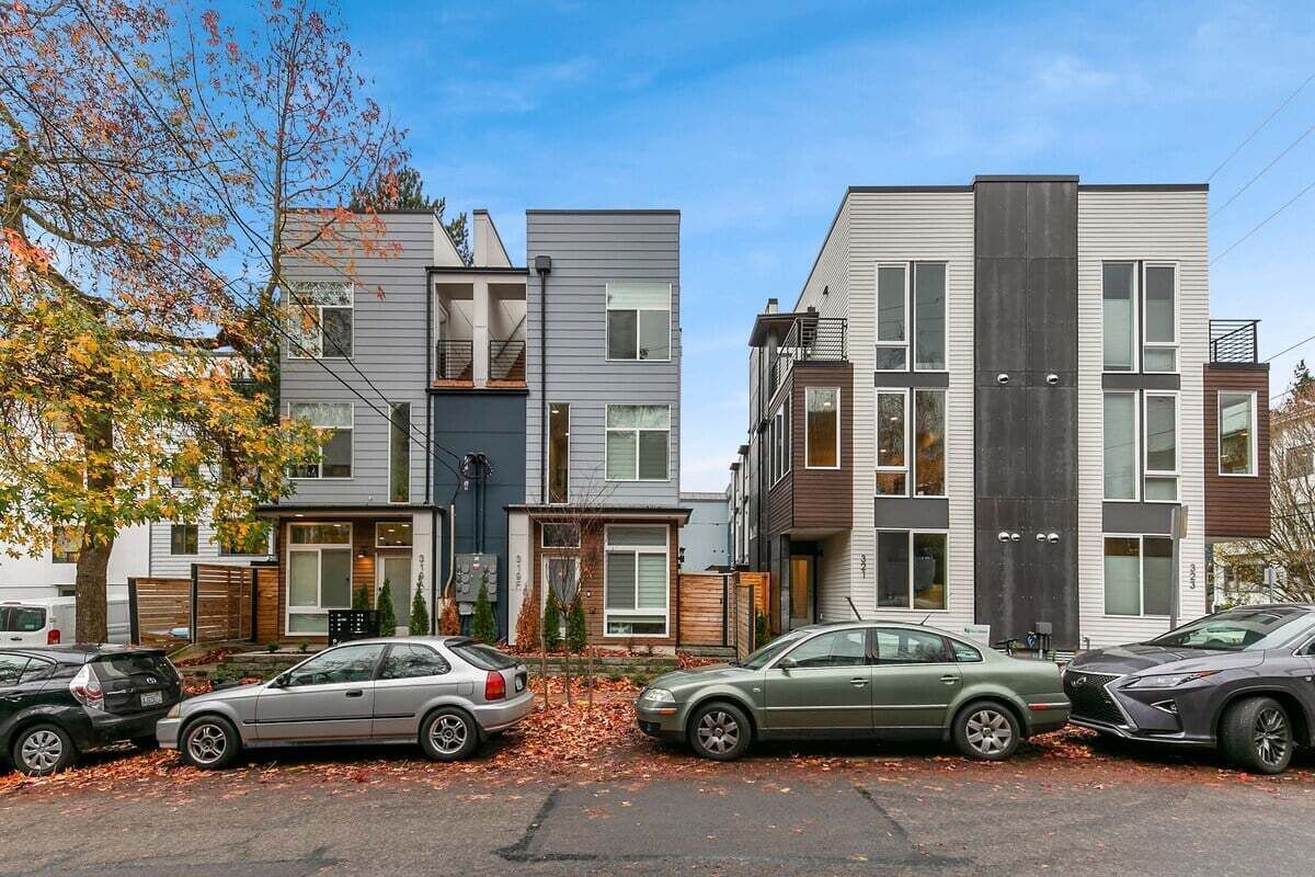 Una hilera de edificios residenciales modernos, de varios pisos, con diferentes estilos de ventanas y un estacionamiento con automóviles.