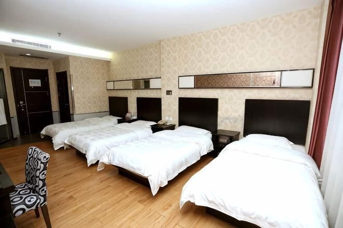 A hotel room with three beds, a desk, and a chair.