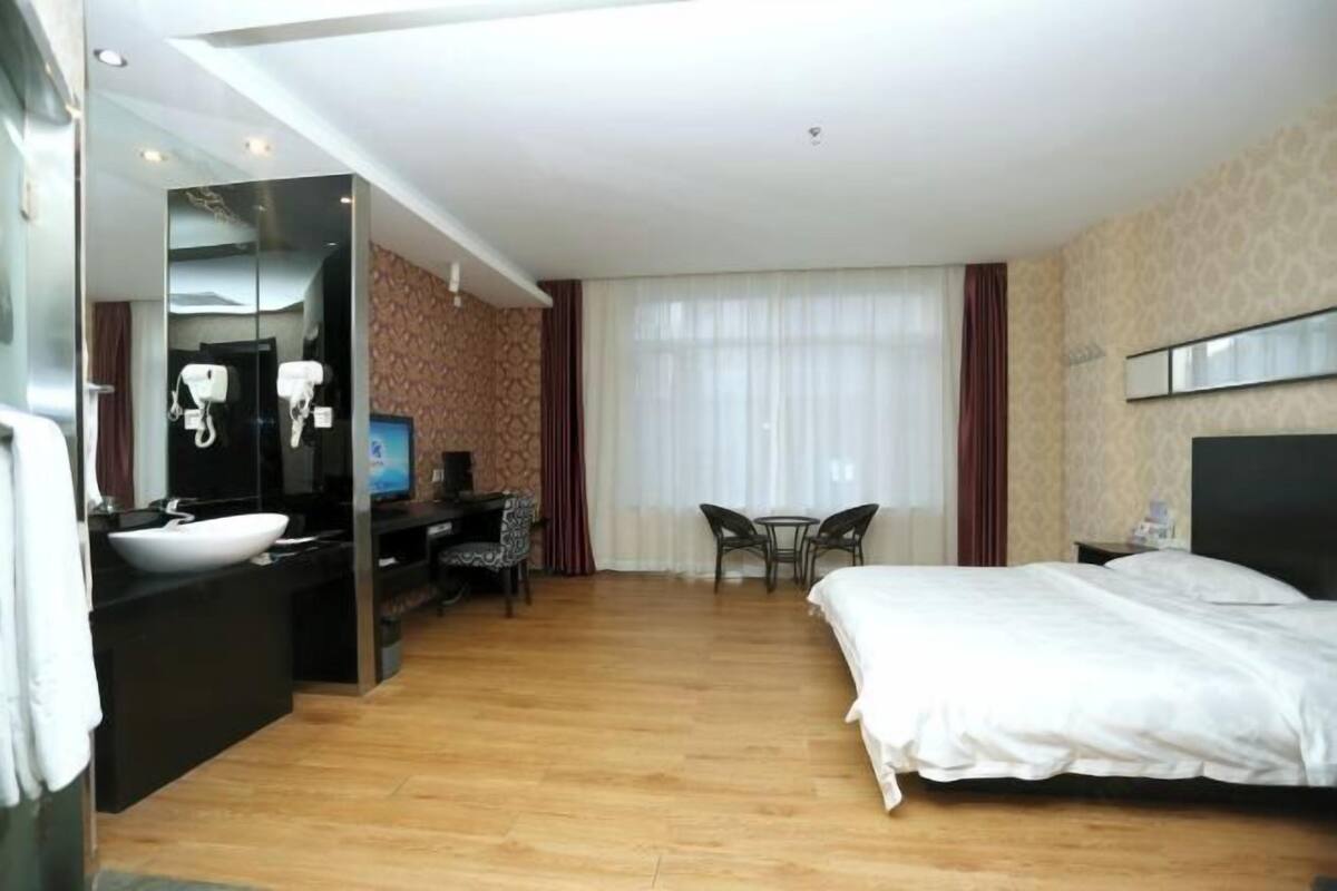 Ett hotellrum med en säng, ett skrivbord med en dator, en spegel, ett handfat och en tv.