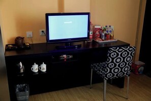 A small, dark-colored desk with a computer monitor displaying a word document. There are two white cups with logos, a small kettle, and a trash bin. A patterned chair is positioned in front of the desk. - Huadu Modern Business Hotel (Jiaohe Boutique) (Jiaohe)